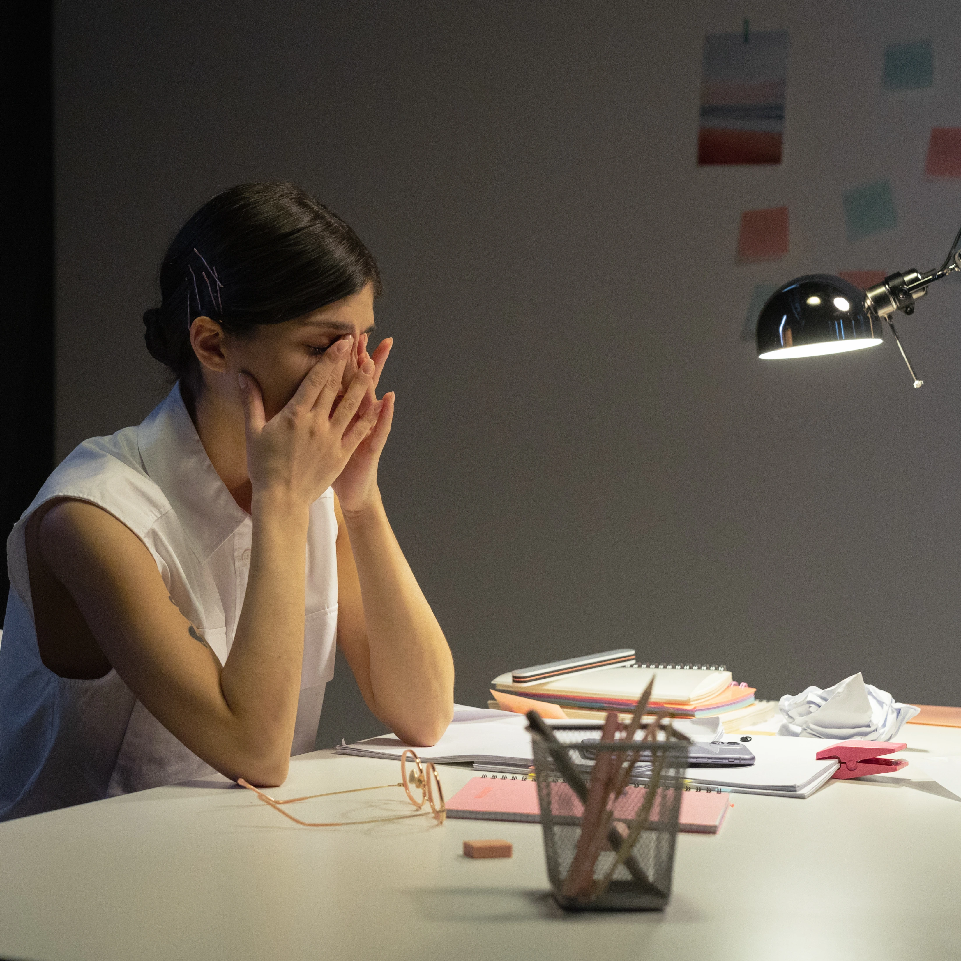 Stressed or tired person rubbing eyes at a desk
