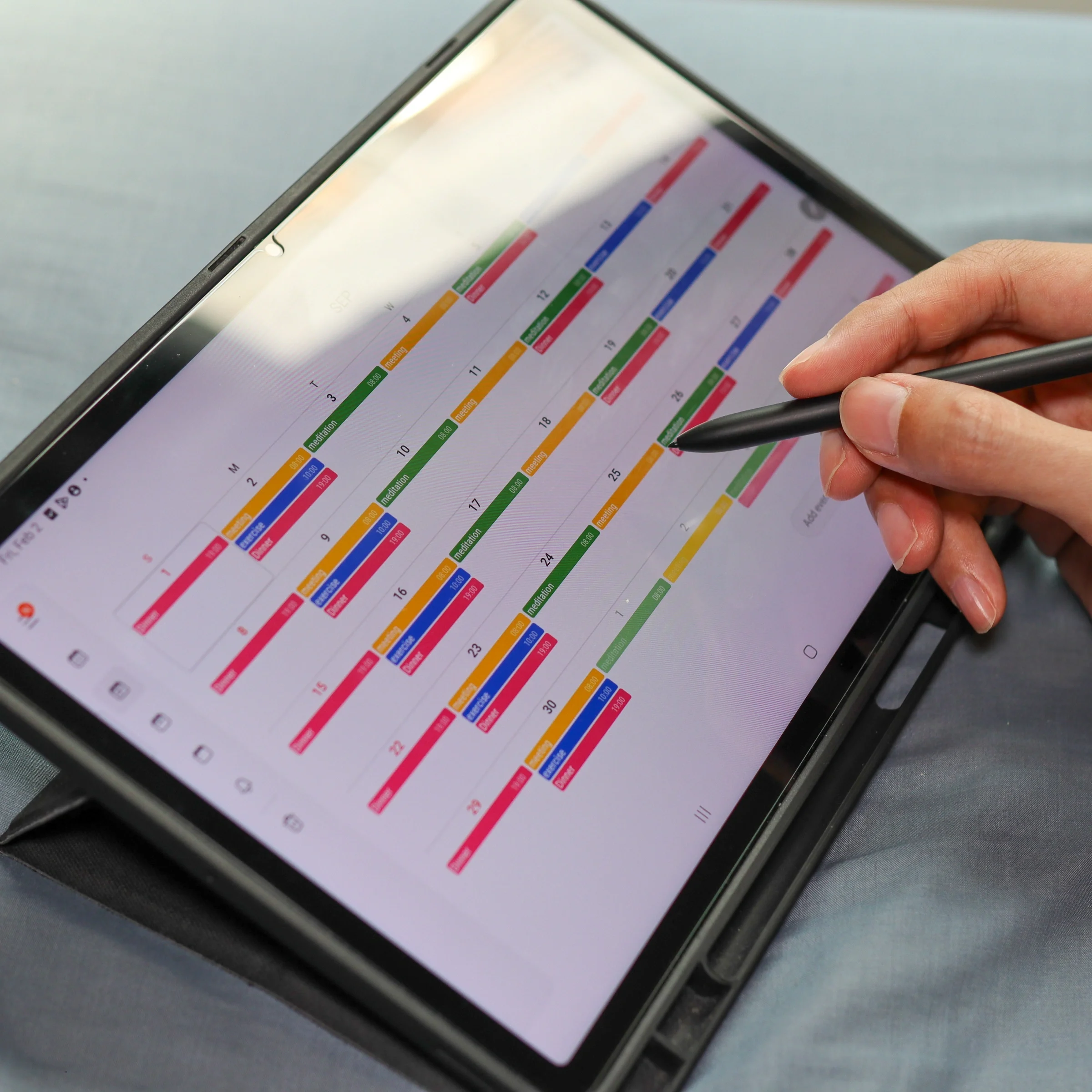 Hand using stylus on tablet calendar