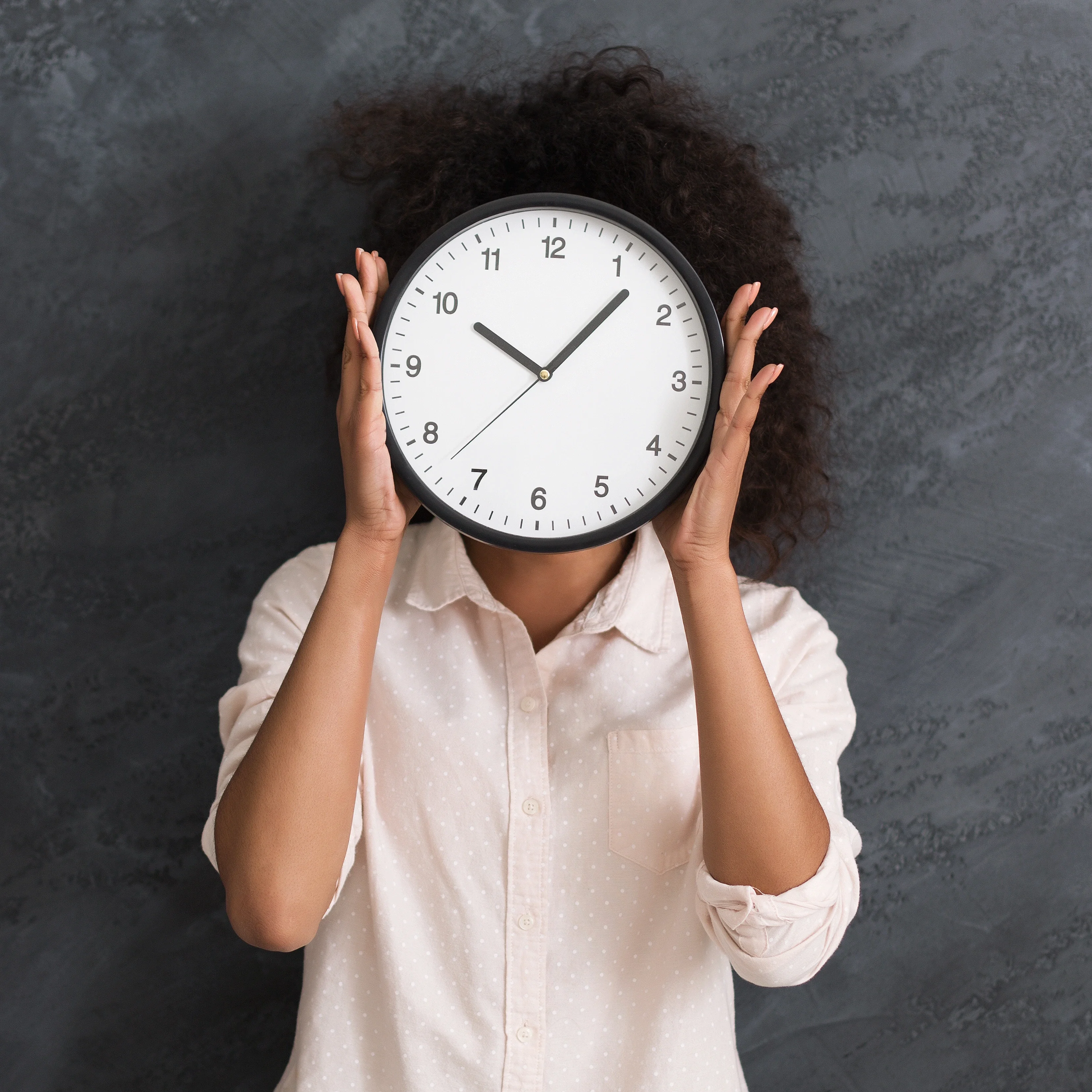 Person hiding face behind a large clock